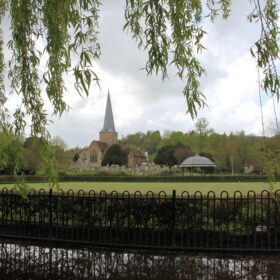 Wrought iron fence in foreground with a view across the Phillips Memorial park towards the Parish Church, taken from under a weeping willow tree on a cloudy day
