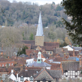 View across rooftops of Godalming showing the cupola of The Pepperpot and the spire of the parish church from the vantage point of St Edmund's Steps with wooded hillside on the opposite side of the valley