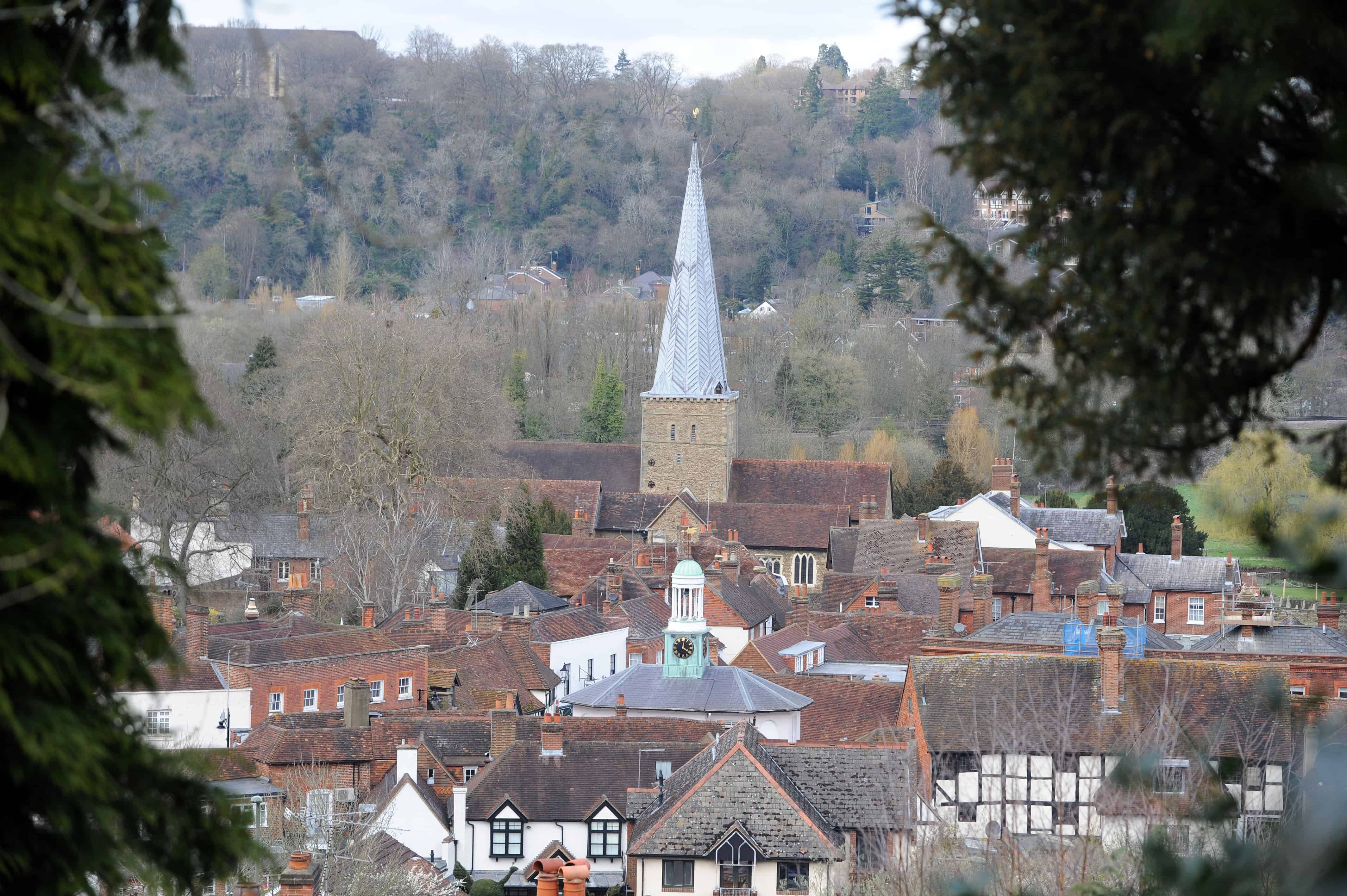 View across rooftops of Godalming showing the cupola of The Pepperpot and the spire of the parish church from the vantage point of St Edmund's Steps with wooded hillside on the opposite side of the valley
