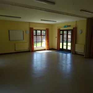 Interior of the Small Hall of Broadwater Park Community Centre looking across the hall towards the doors where the sunny garden beyond can be seen